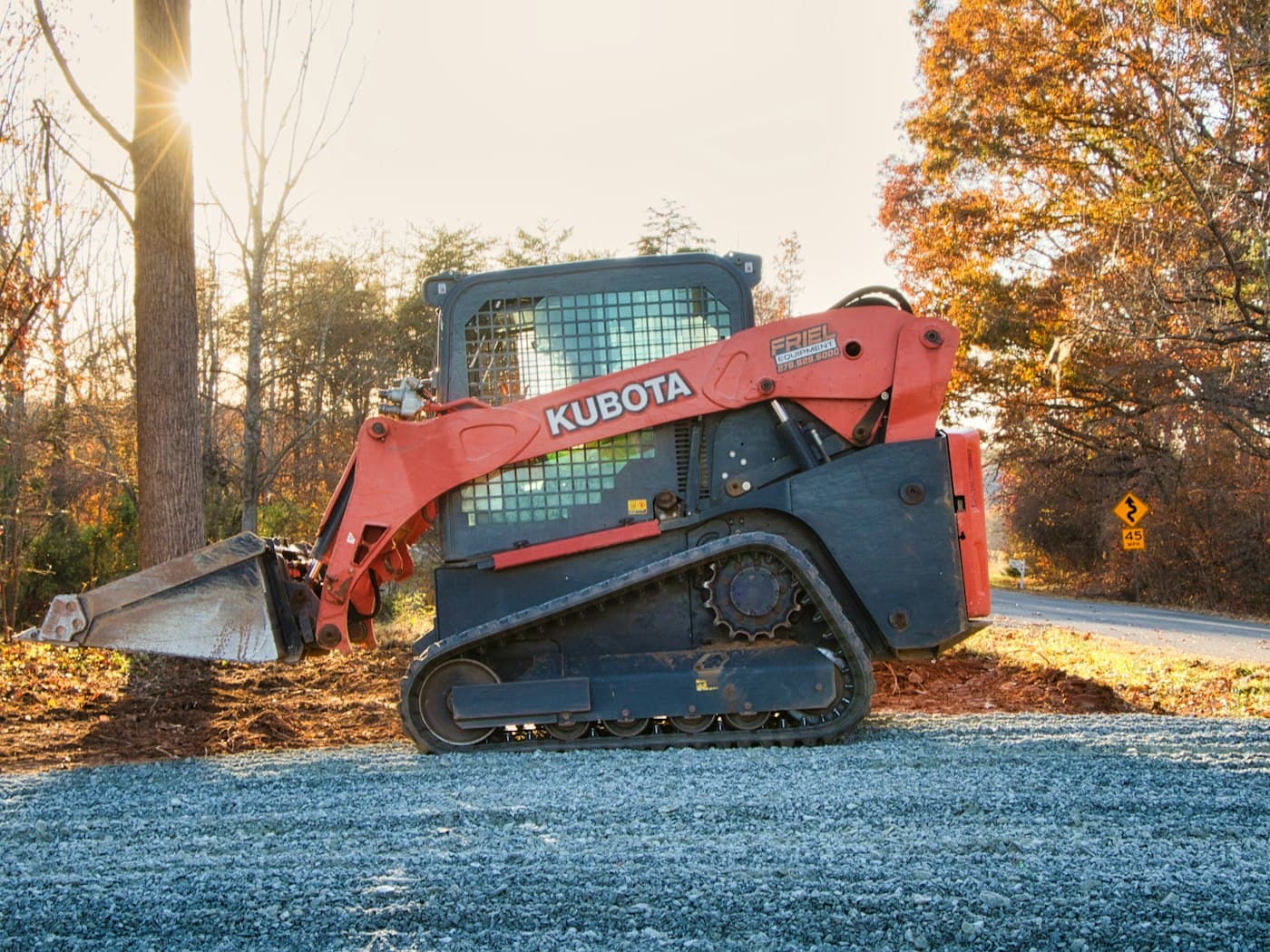 A skid steer loader standing on gravel.